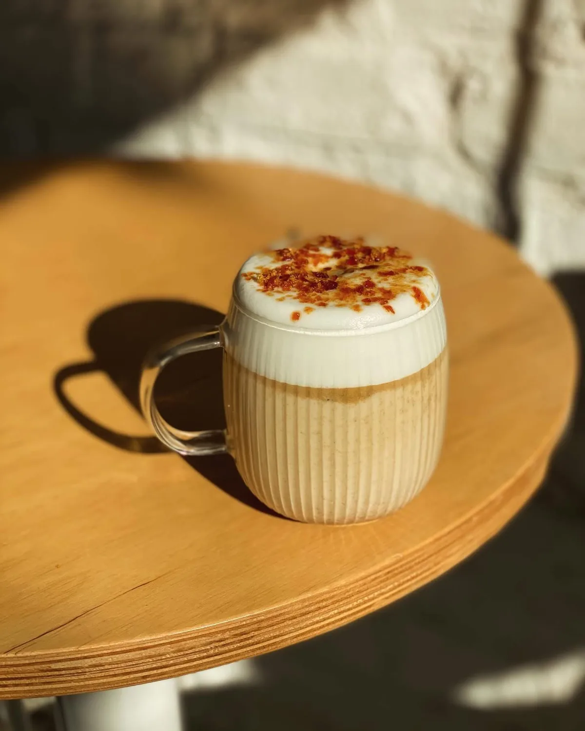 Latte z karmelową kruszonką na drewnianym stoliku